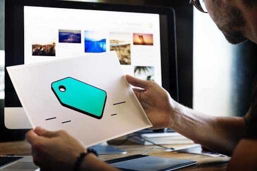 How to add depth to your designs. 1 A man looks at a desktop screen while holding a piece of paper with a price tag graphic on it.
