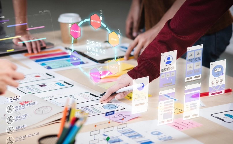 People standing around a table, writing on mockups of mobile screens.