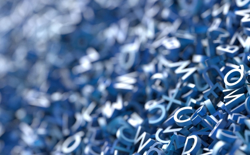 Jumble of blue, three-dimensional letters of the alphabet in a pile.